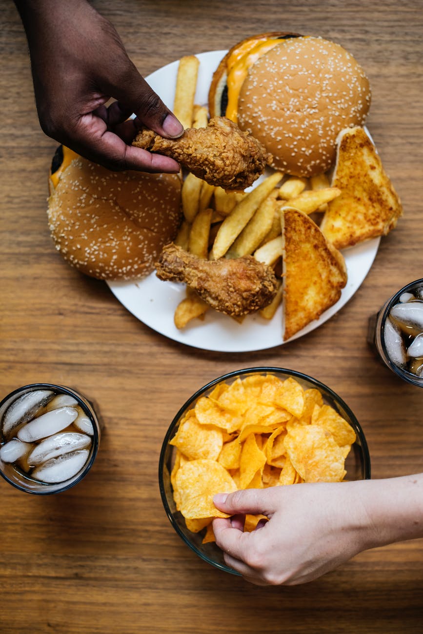 two people holding chips and fried chicken
